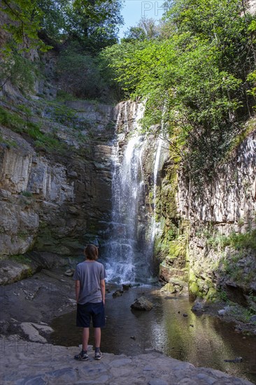 Junger Mann vor den Sulphur Wasserfall bei den Schwefelbaeder in Abanotubani