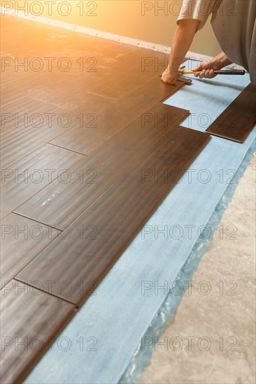 Man installing new laminate wood flooring abstract