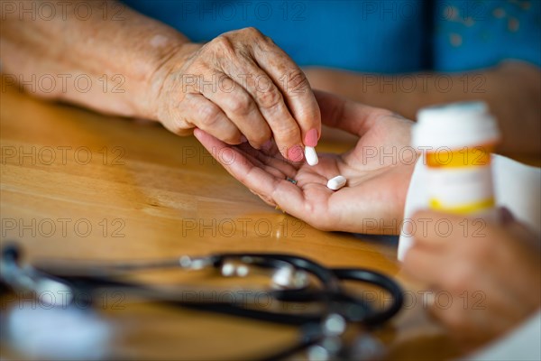 Senior adult woman taking medicine pill from doctors palm