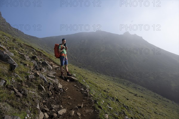 Hikers on trail through moss-covered mountain landscape