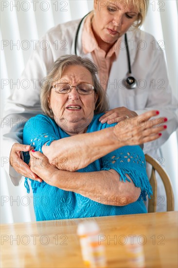 Female doctor helping senior adult woman with arm exercises