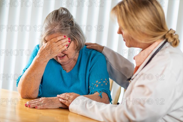 Female doctor consoling distraught senior adult woman