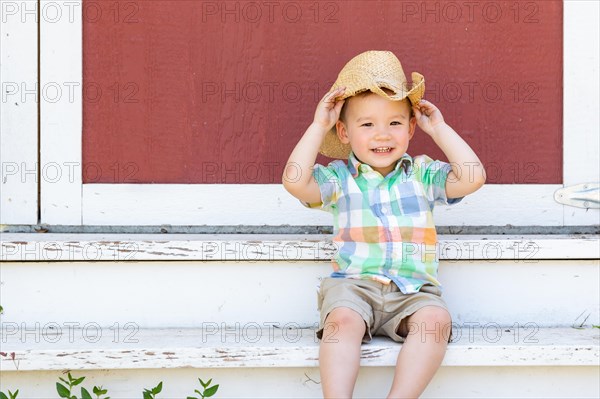 Young mixed-race chinese and caucasian boy wearing cowboy hat relaxing on the steps