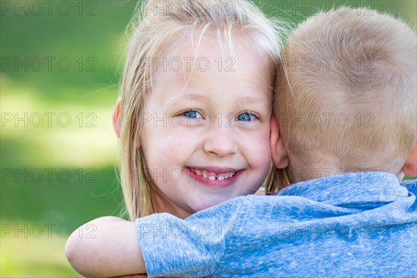 Young brother and sister hugging at the park
