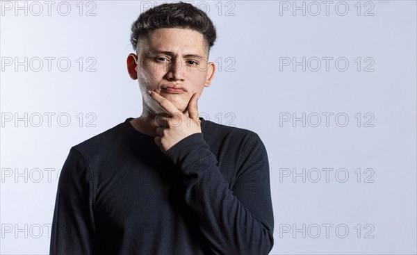 Young man wondering with his hand on his chin on an isolated background