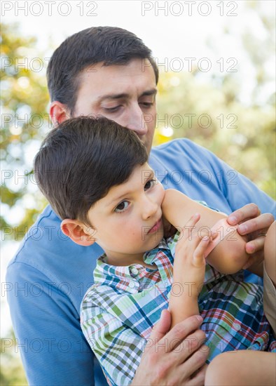 Loving father puts a bandage on the elbow of his young son in the park