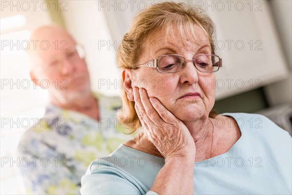 Senior adult man standing behind sad senior adult female