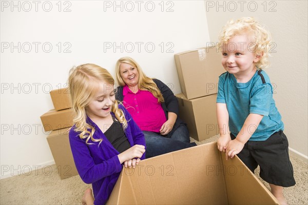 Playful young family in empty room playing with moving boxes