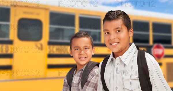 Young hispanic boys walking near school bus