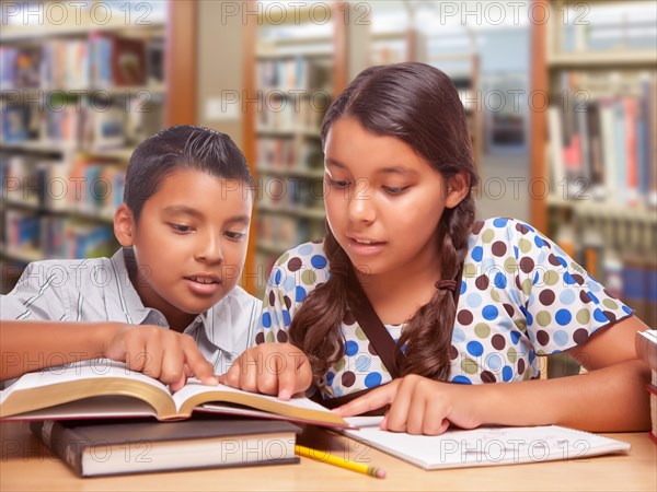 Hispanic boy and girl having fun studying together in the library