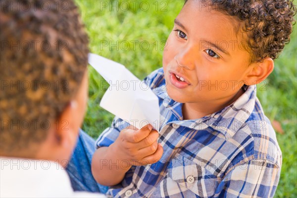 Happy african american father and mixed-race son playing with paper airplanes in the park