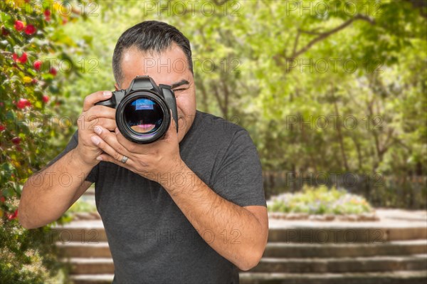 Hispanic young male photographer with DSLR camera outdoors