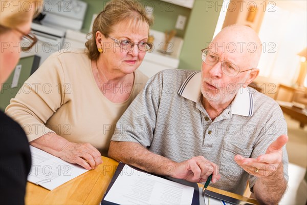 Senior adult couple going over documents in their home with agent at signing