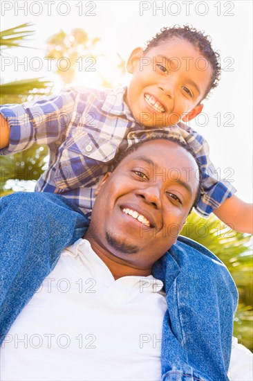 mixed-race son and african american father playing piggyback outdoors together