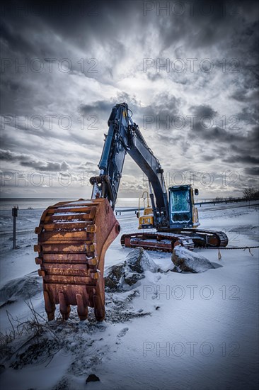 Old excavator with excavator bucket in winter