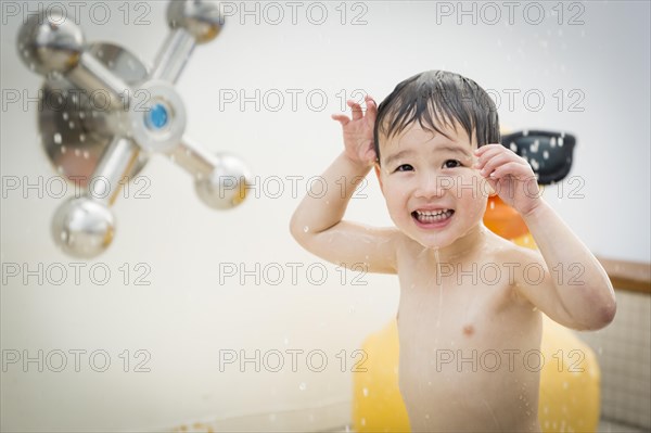 mixed-race boy having fun at the water park with large rubber duck in the background