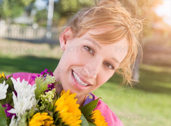 Outdoor portrait of an excited young adult brown eyed woman holding a bouquet of flowers
