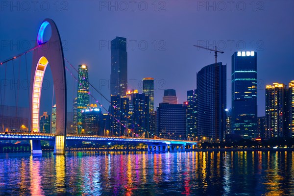 Guangzhou cityscape skyline over the Pearl River with Liede Bridge illuminated in the evening. Guangzhou