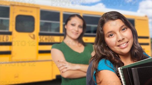 Hispanic mother and daughter near school bus