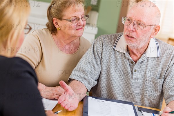 Senior adult couple going over documents in their home with agent at signing