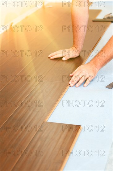 Man installing new laminate wood flooring abstract