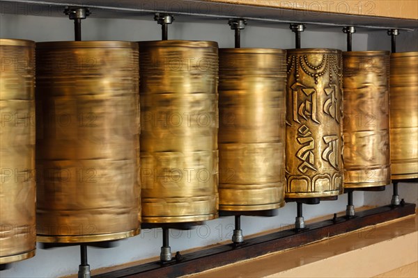 Rotating motion blurred metal buddhist prayer wheels with Om Mani Padme Hum mantra meaning Praise to Jewel in Lotus in Tsuglagkhang complex in Dalai Lama residence