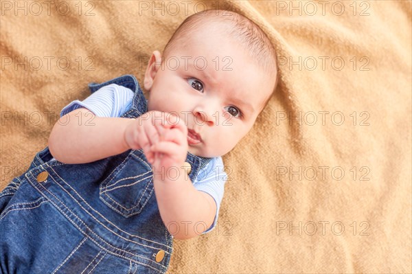 Happy mixed-race baby boy laying on blanket