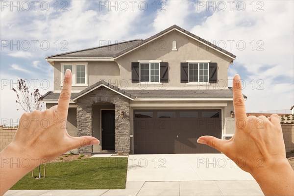 Female hands framing beautiful newly constructed house