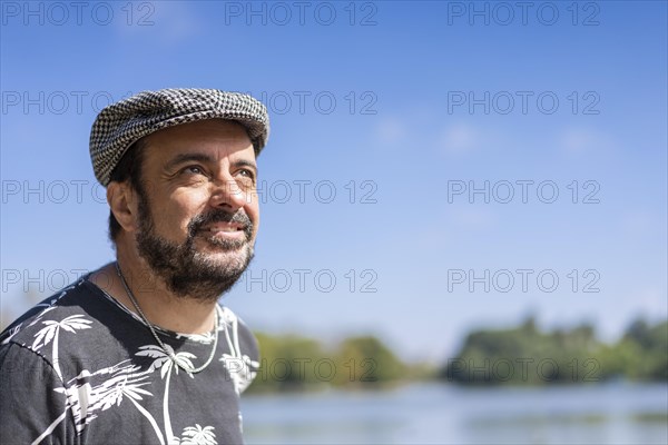 Bearded mature man wearing a beret at a lake. Copy space