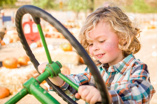 Little boy having fun in A tractor in a rustic ranch setting at the pumpkin patch