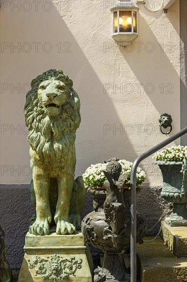 Bronze lion and little angel with flowers in front of facade