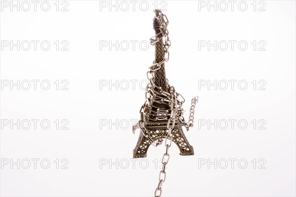 Little model Eiffel Tower in chains on a white background