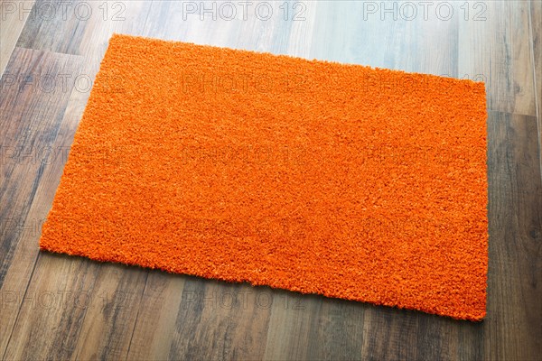 Blank orange welcome mat on wood floor background ready for your own text