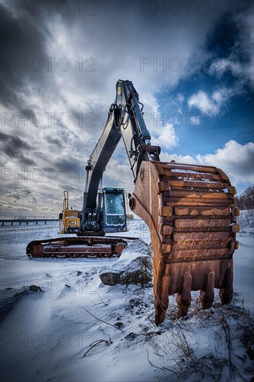 Old excavator with excavator bucket in winter. Road construction in snow. Lofoten islands