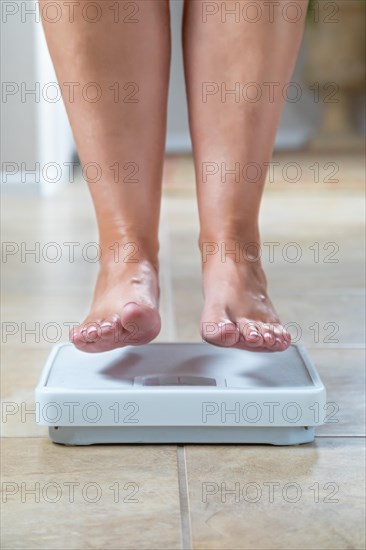 Woman floating slightly above surface of weight scale