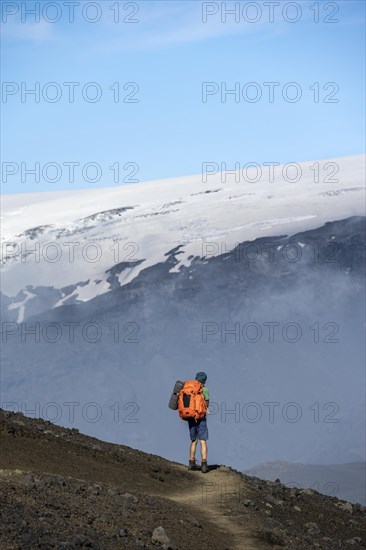 Hikers on trail through volcanic landscape