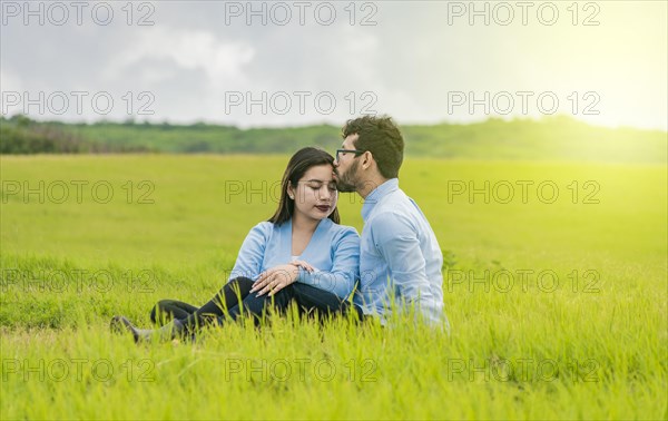 A couple in love sitting in the field kissing their foreheads
