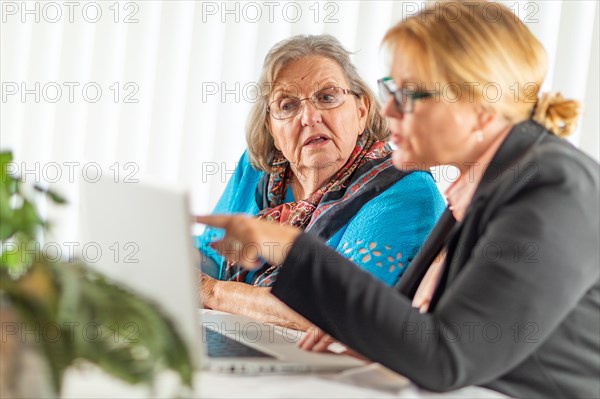 Woman helping senior adult lady on laptop computer