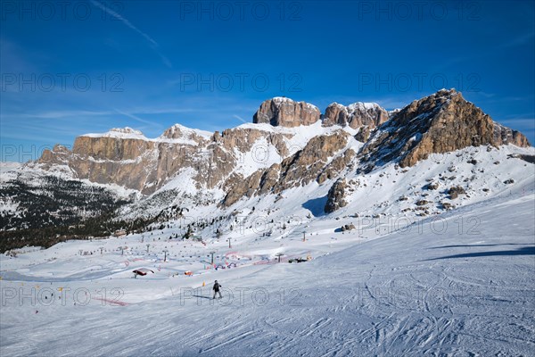 View of a ski resort piste with people skiing in Dolomites in Italy