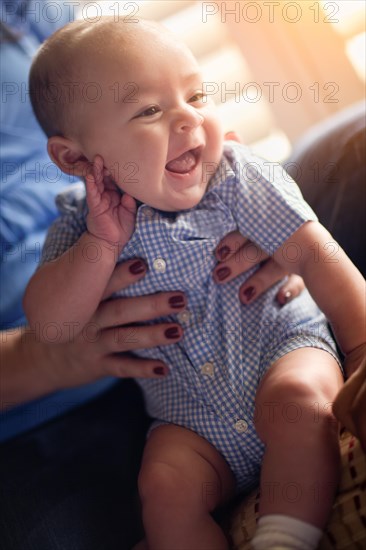 Happy mixed-race couple enjoying their newborn son in the light of the window