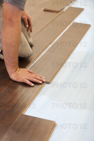 Man installing new laminate wood flooring abstract