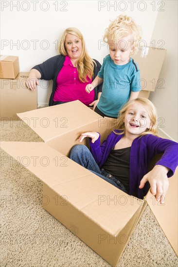 Playful young family in empty room playing with moving boxes