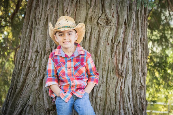 mixed-race young boy wearing cowboy hat standing outdoors