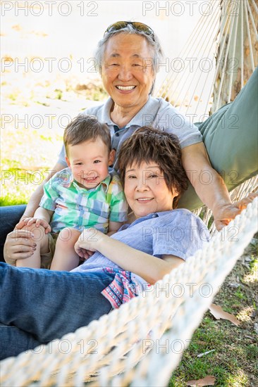 Chinese grandparents in hammock with mixed-race child