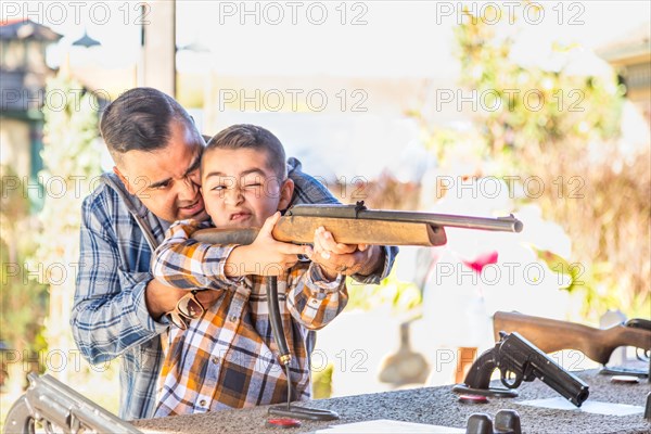 mixed-race father and son at fairground shooting range