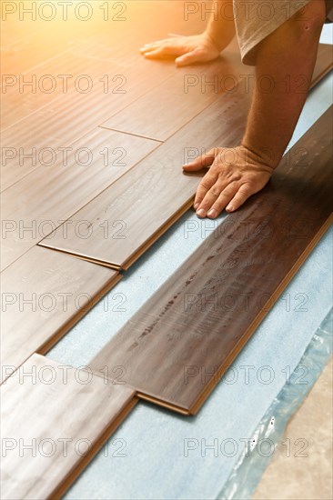 Man installing new laminate wood flooring abstract