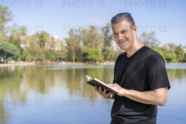 Mature man reading by a lake