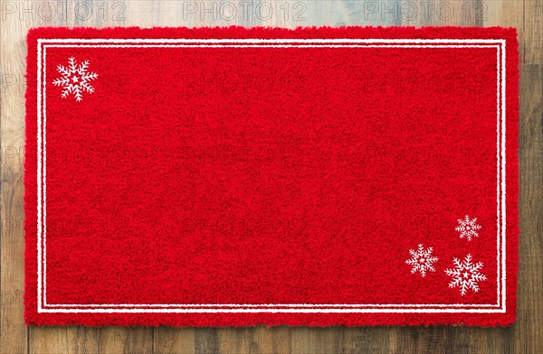 Blank holiday red welcome mat with snow flakes on wood floor background