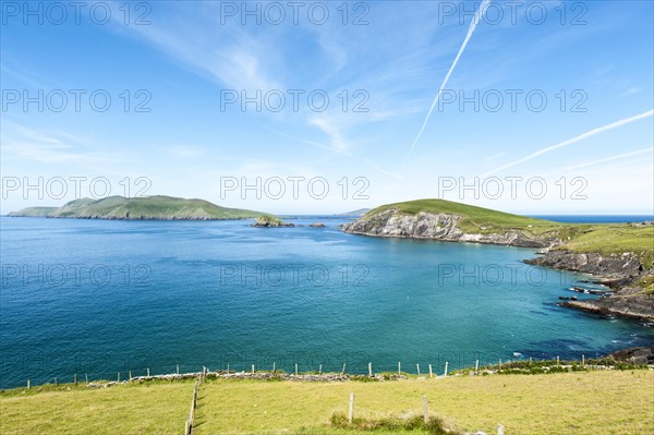 View of green coastal landscape with Blasket Islands behind left