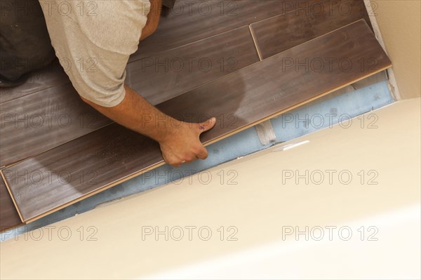 Man installing new laminate wood flooring abstract